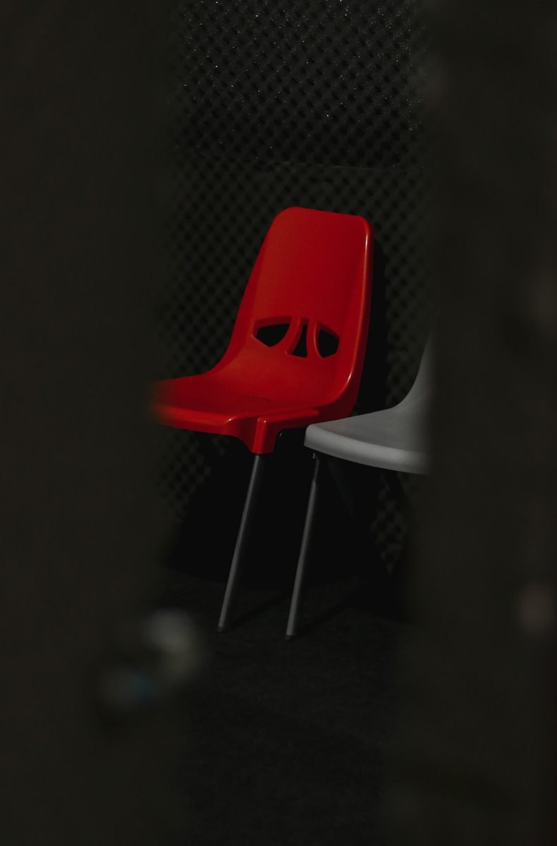 a red chair with eyes on it sitting next to a white chair