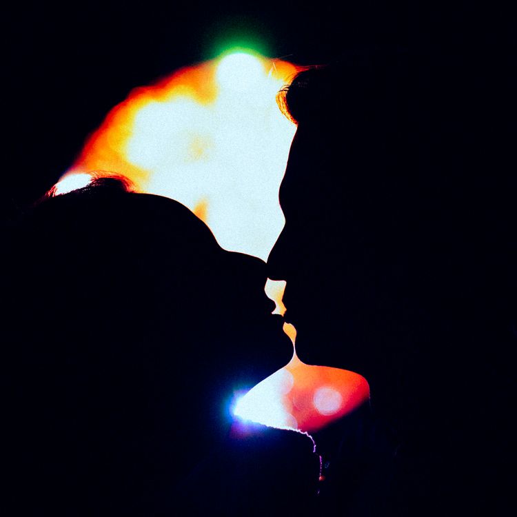 Silhouette of a couple kissing with vibrant romantic lights behind them