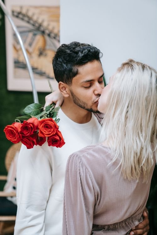 Loving couple sharing a tender kiss with red roses
