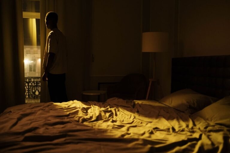 Man in a dimly lit bedroom, intimate and contemplative mood